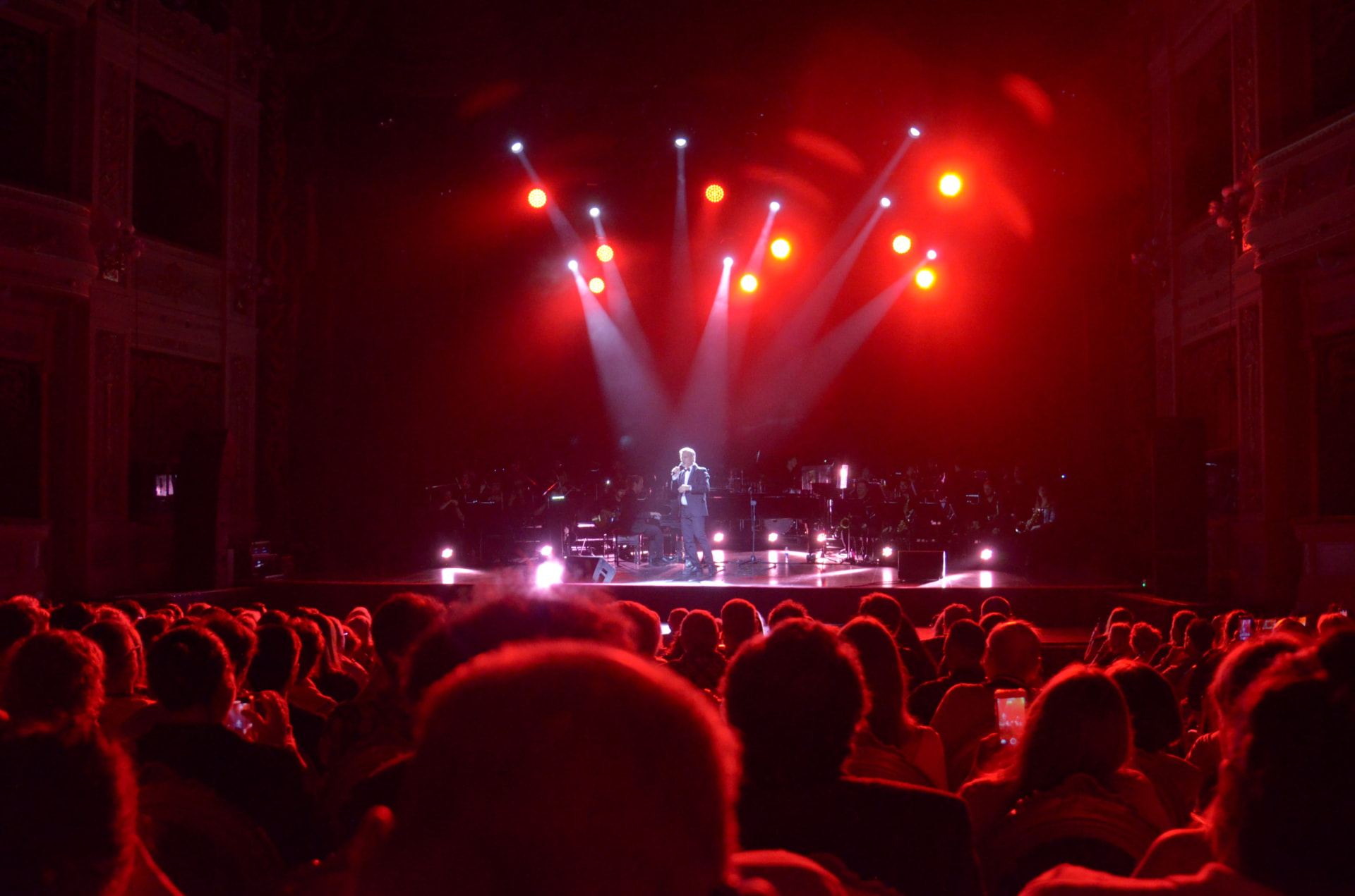 Christian Valverde en el escenario del teatro con luces rojas frente al público
